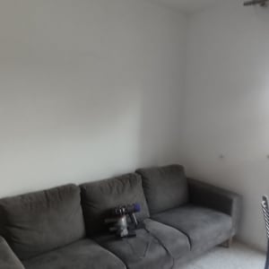 שואב אבק על ספה בחדר עם קירות לבנים