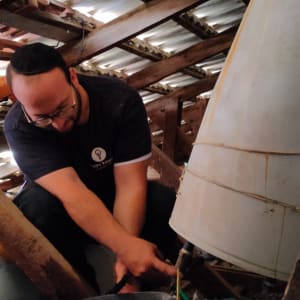 אדם מתקן דוד שמש בעליית גג עם דלי