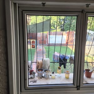 חלון זכוכית עם אדן מלא בעציצים וכוסות