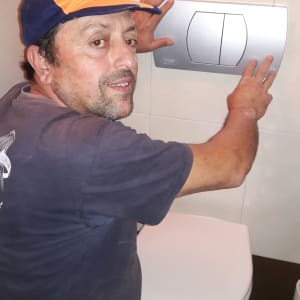 אדם מתקין לחצן הדחה בשירותים