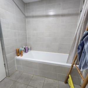 חדר אמבטיה עם אריחים אפורים ואמבטיה לבנה