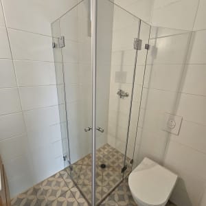 מקלחון זכוכית עם דלתות מתכת בחדר אמבטיה