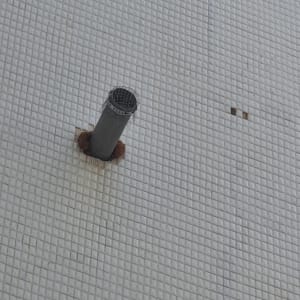 צינור מתכת בולט מקיר מרוצף