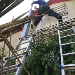 אדם על סולם מתקין חלק מתכת על גג