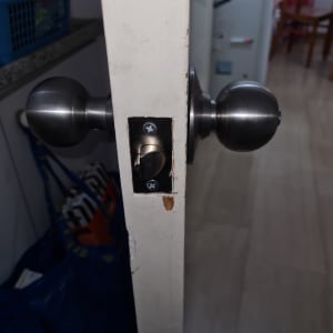 ידית דלת מתכתית מותקנת על דלת עץ לבנה