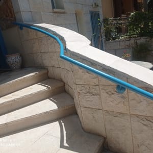 מעקה כחול על קיר אבן ליד מדרגות