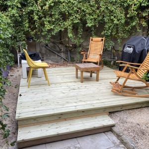 דק עץ עם כיסאות נדנדה ושולחן קטן בגינה