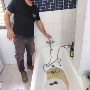 אדם בודק נזילות באמבטיה עם מד לחץ