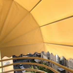 סוכך צהוב עם קשתות מתכת על מרפסת