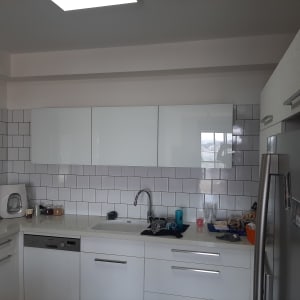 מטבח מודרני עם ארונות לבנים ומקרר נירוסטה