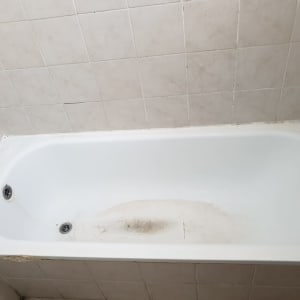 אמבטיה לבנה עם כתמים, אריחים בהירים על הקיר