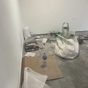 חדר עם שקיות, קרטונים ובקבוק על הרצפה