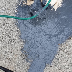 חומר איטום אפור נמרח על גג ליד צינורות