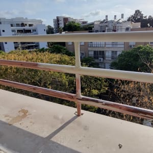 מעקה מתכת במרפסת עם נוף של בניינים ועצים