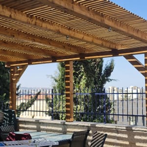 פרגולה מעץ עם קורות אופקיות בגינה