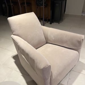 כורסה מרופדת בבד בהיר עם משענות רחבות