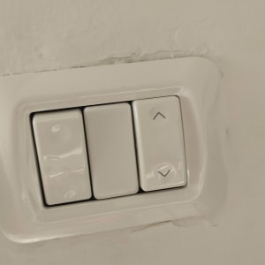 מתג חשמלי עם שלושה כפתורים על קיר לבן