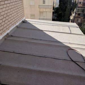 גג אטום עם חומר איטום לבן לאורך הקיר