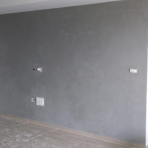 קיר צבוע באפור עם דלי צבע על הרצפה