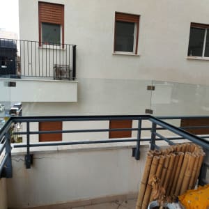 מעקה זכוכית במרפסת עם חיבורים מתכתיים