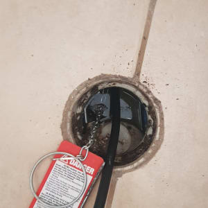 כבל שחור עם תג אזהרה אדום בתוך פתח ניקוז