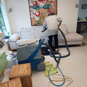 אדם מנקה ספה עם מכונת ניקוי מקצועית