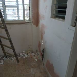 קיר עם תיקוני טיח ורצפה עם שברי טיח