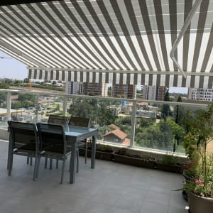 סוכך פסים לבן ואפור במרפסת שמש