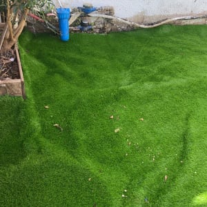 צינור מים כחול ליד קיר לבן ודשא ירוק