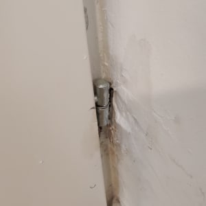 ציר דלת מתכת מותקן בקיר עם סדקים