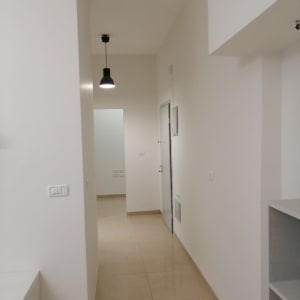 מסדרון עם קירות צבועים בלבן ותאורה תלויה