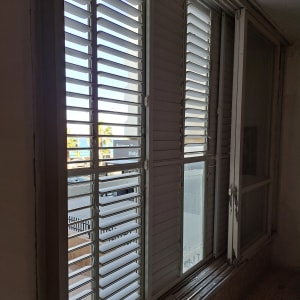 תריסים לבנים פתוחים למחצה בחלון זכוכית