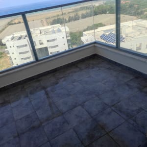 מרפסת עם רצפת אריחים כהים ומעקה זכוכית