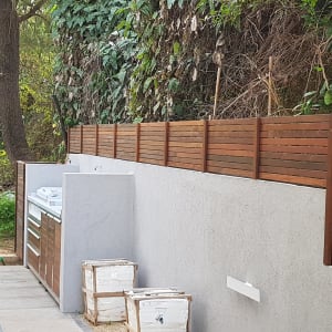 גדר עץ חומה ליד קיר בטון בגינה