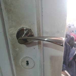 ידית דלת מתכתית ומנעול על דלת לבנה