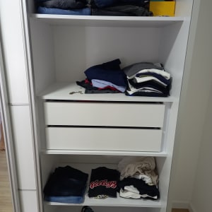 בגדים מקופלים בארון לבן עם מדפים