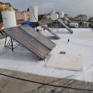 גג אטום בצבע לבן עם קולטי שמש ודודי מים