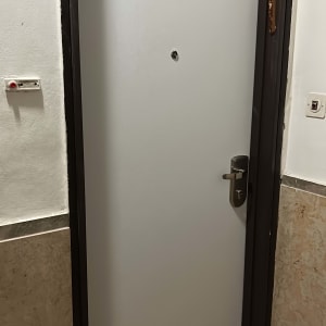 דלת מתכת אפורה עם ידית כסופה ומסגרת כהה