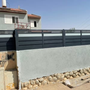 שער חשמלי מתכת כהה עם לוחות אופקיים