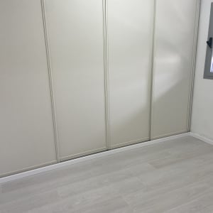 רצפת פרקט עץ בהירה בחדר עם קיר לבן