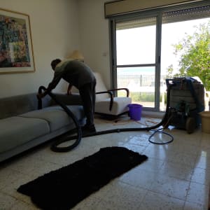 אדם מנקה ספה עם שואב אבק מקצועי