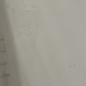 קיר עם סדקים וכתמי רטיבות ליד תקרה