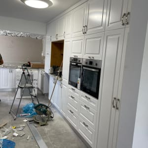 מטבח עם ארונות לבנים, סולם וכלי עבודה על הרצפה