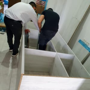 שני אנשים מרכיבים ארון עץ בחדר