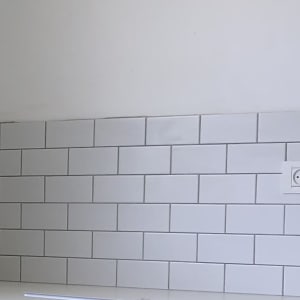 אריחי קרמיקה לבנים על קיר עם שקע חשמל