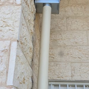 צינור אטום עם קופסת מתכת על קיר אבן