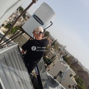 אדם עובד על דוד שמש על גג בניין