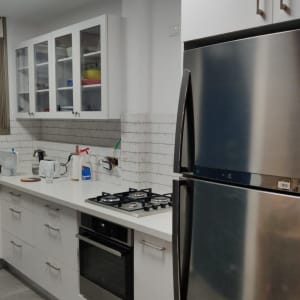 מטבח עם מקרר, כיריים, כיור וארונות לבנים