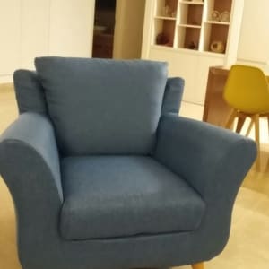 כורסה מרופדת בכחול עם רגלי עץ