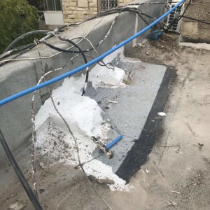 חומר איטום לבן על גג עם צינורות חשמל